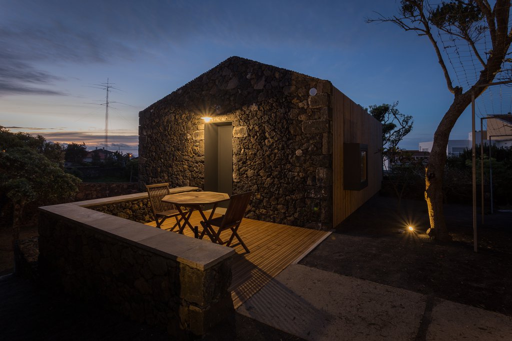Studio accommodations/lodging at Quinta dos Peixes Falantes: exterior basalt façade entrance with private patio at dusk
