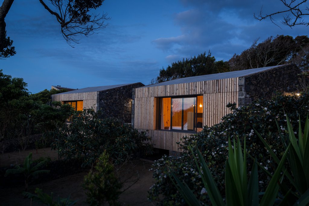 Studio accommodations/lodging at Quinta dos Peixes Falantes: studio exteriors finished in timber slats and dense gardens by sunset