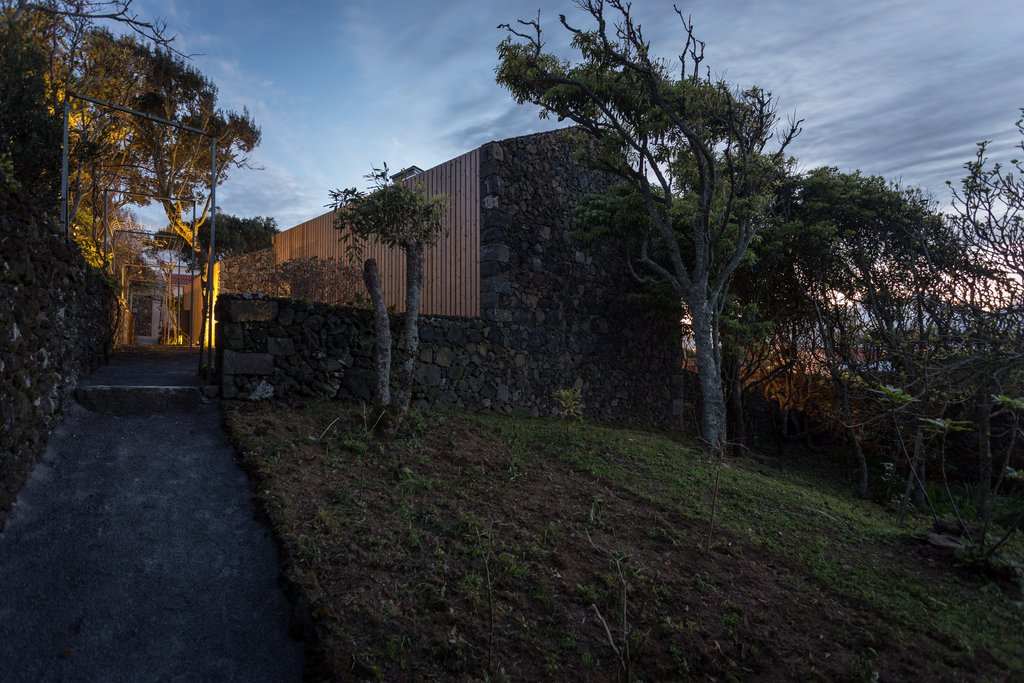  Studio accommodations/lodging at Quinta dos Peixes Falantes: exterior corner finished in timber slats and basalt with path to garden